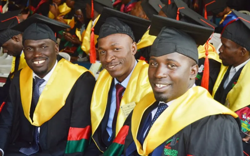 Makerere graduates smiling in gowns at a graduation ceremony