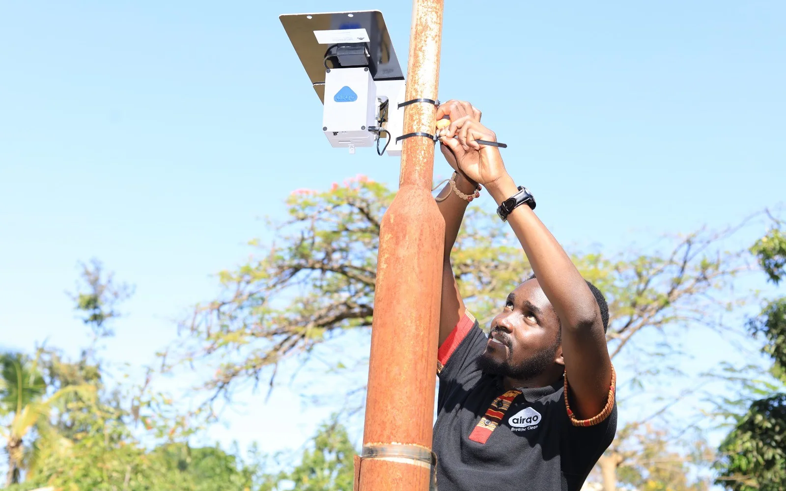 An AirQo team member fixing an air-quality monitor to a pole
