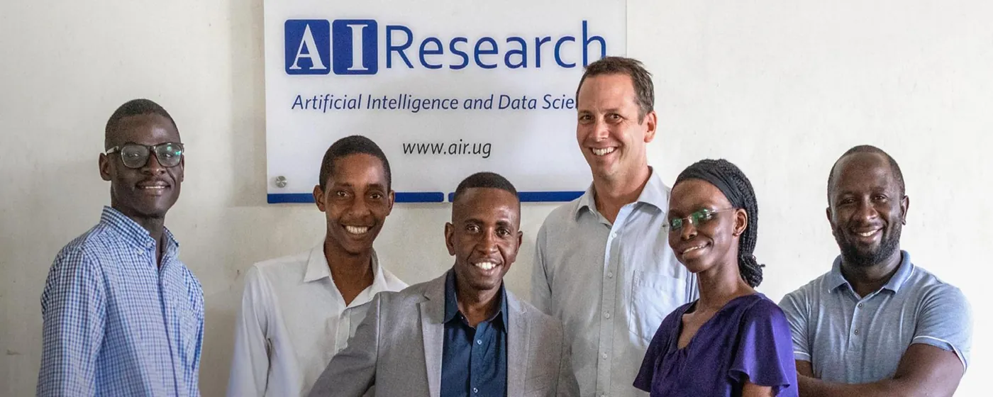 Members of the Artificial Intelligence and Data Science research lab standing in front of the lab sign